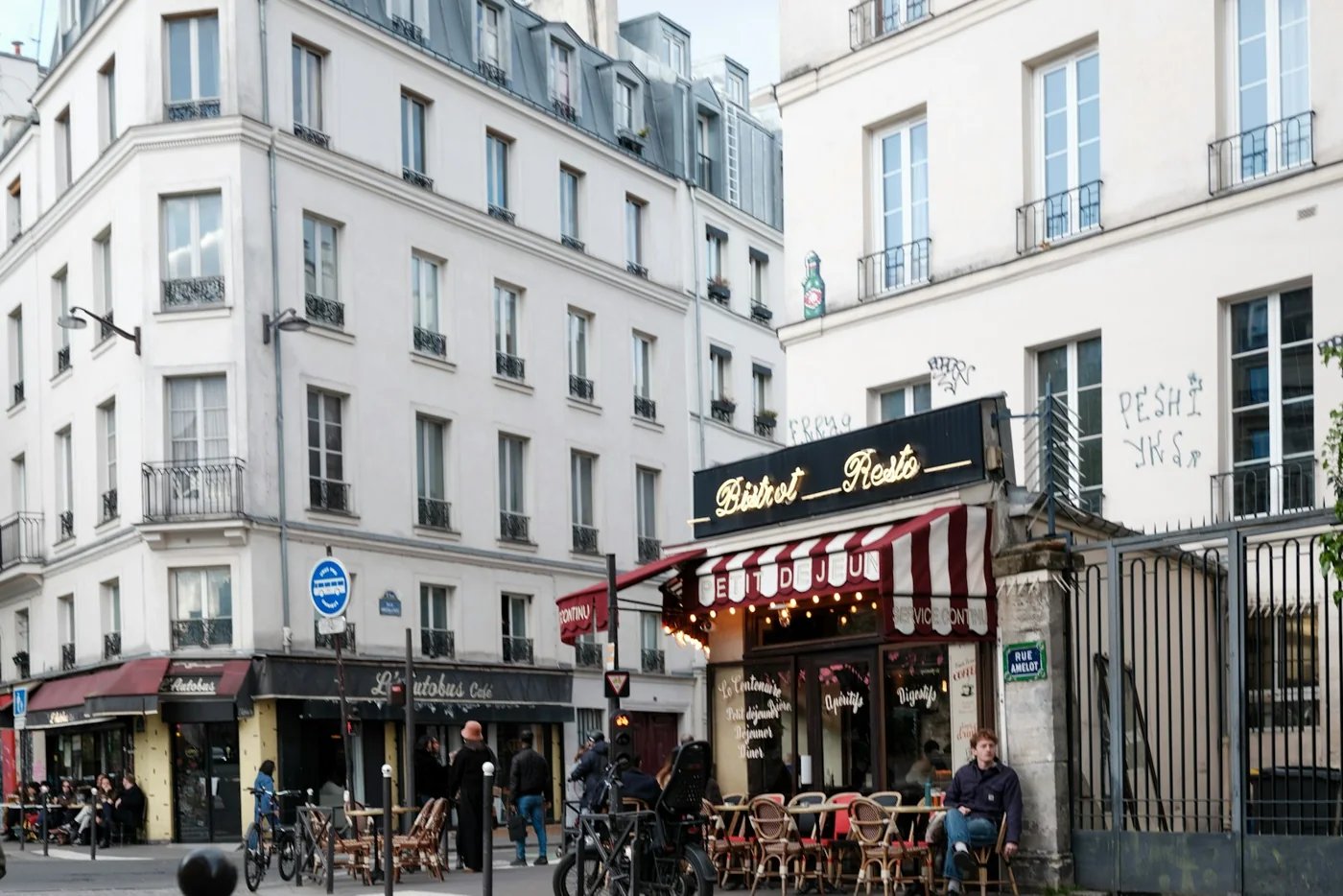 Outdoor tables at a Paris neighborhood café beneath a red awning